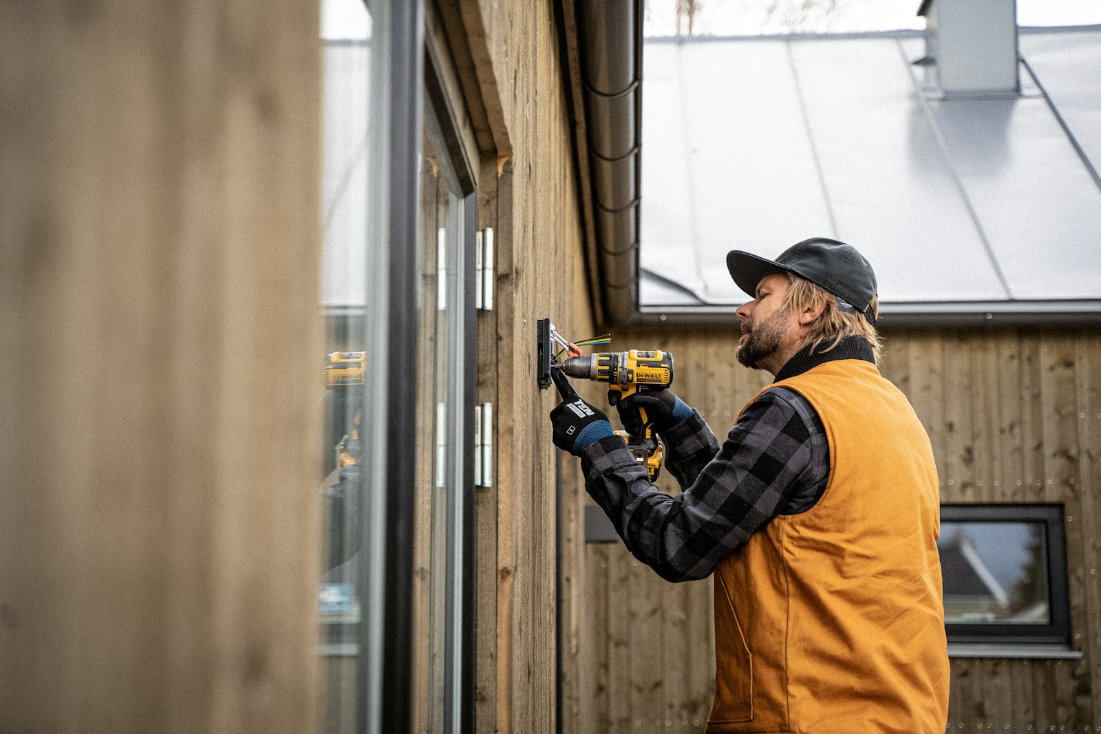 A tradesperson using a power drill on a timber building