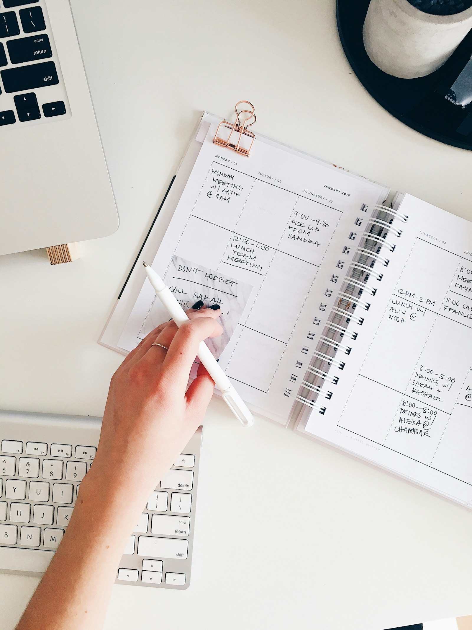 Hand writing in a planner on a clean desk