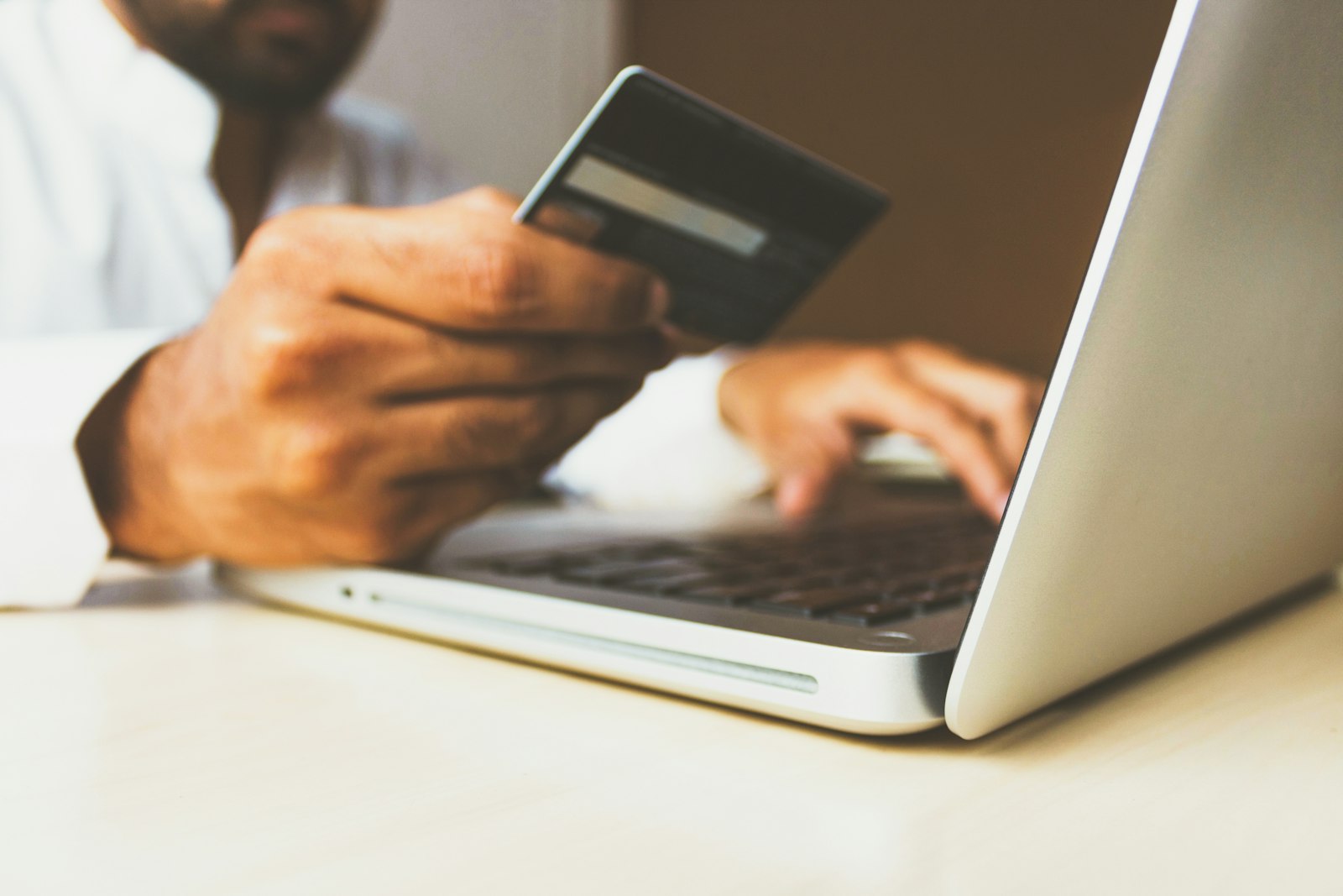Person holding a bank card while using a laptop to pay online