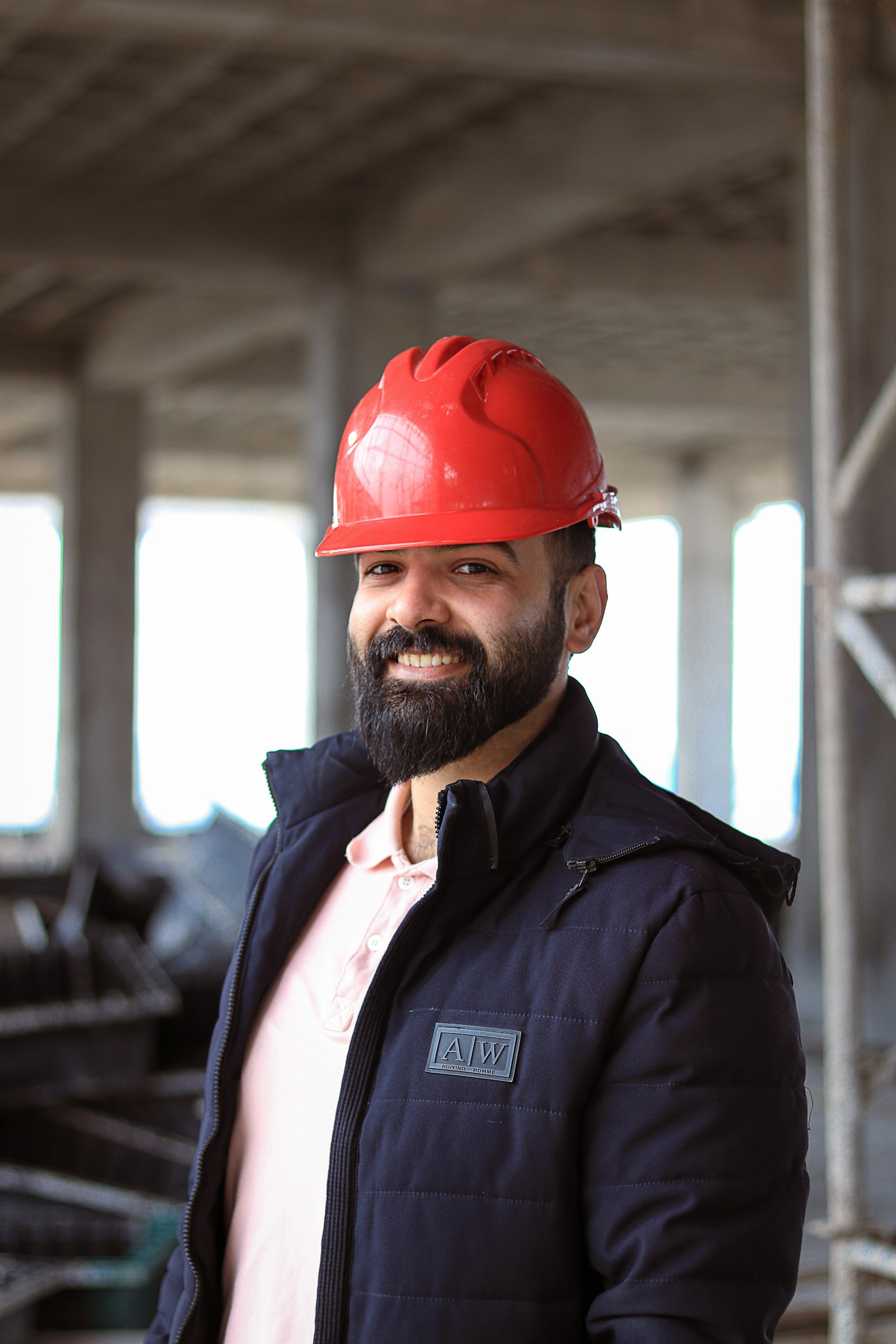 Smiling contractor in a red hard hat on a building site